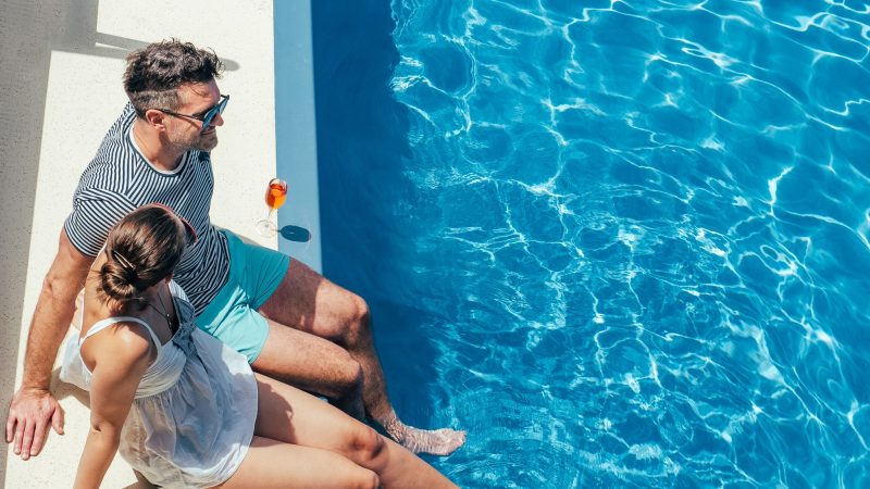 Young couple in love sitting by the pool on the empty deck of a cruise liner. Closeup, outdoor, view from above. Vacation and travel concept